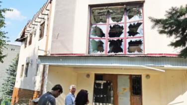 People examine a damaged building in war-torn Ukraine.
