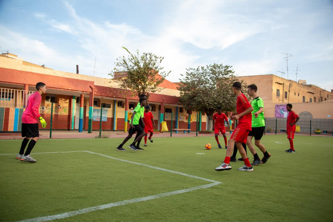 Groupe de jeunes garçons entrain de jouer un match de foot sur le terrain à l'extérieur