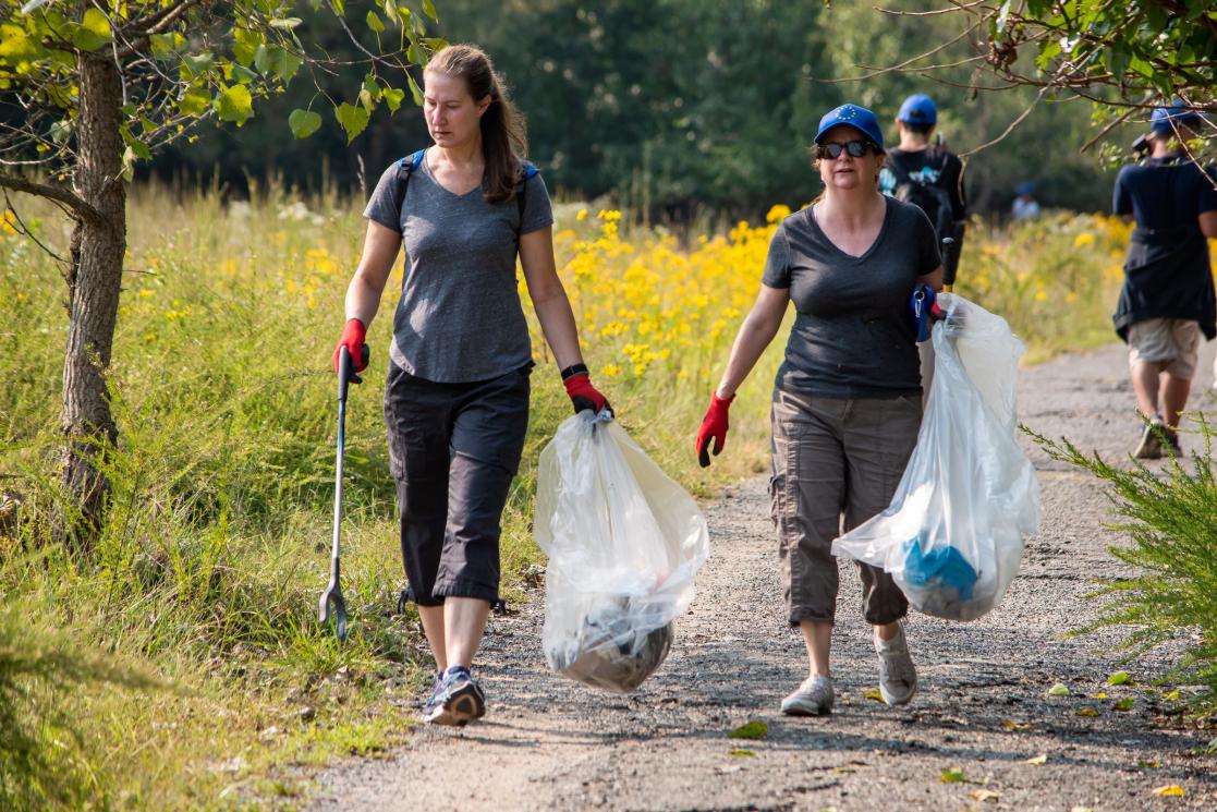 Two volunteers carry bags of trash through Kenilworth Park.