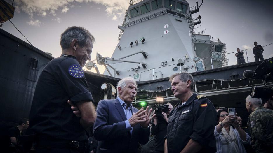 HRVP Josep Borrell in discussions with military commanders with a naval warship in the background.