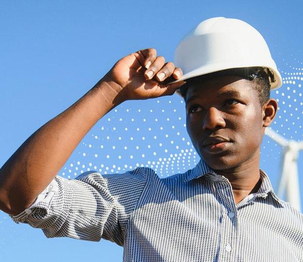 Man with a hard hat in front of a wind turbine
