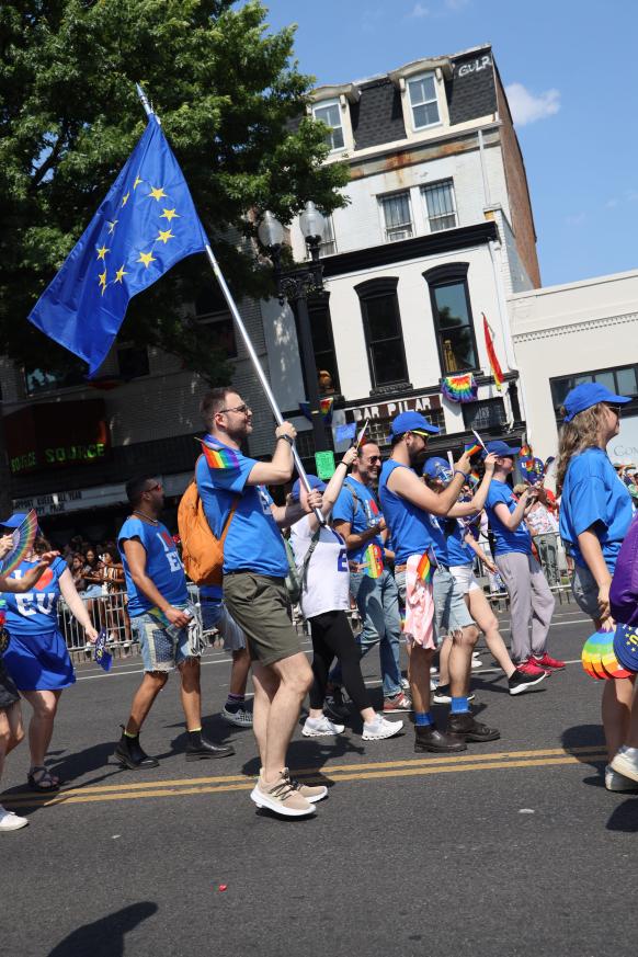 One person holds a large EU flag while marching alongside other people.