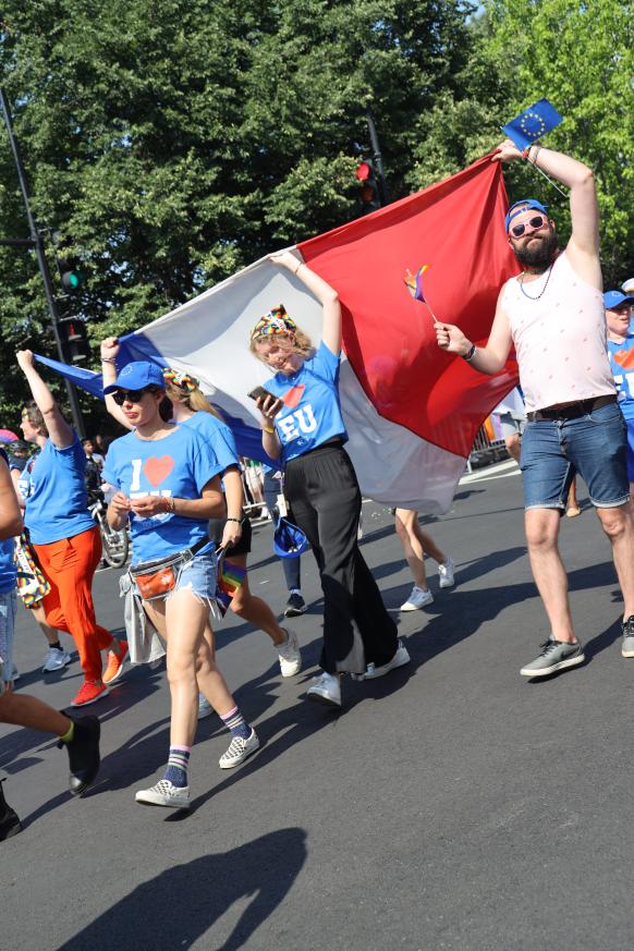 EU parade marchers carry a large French flag.