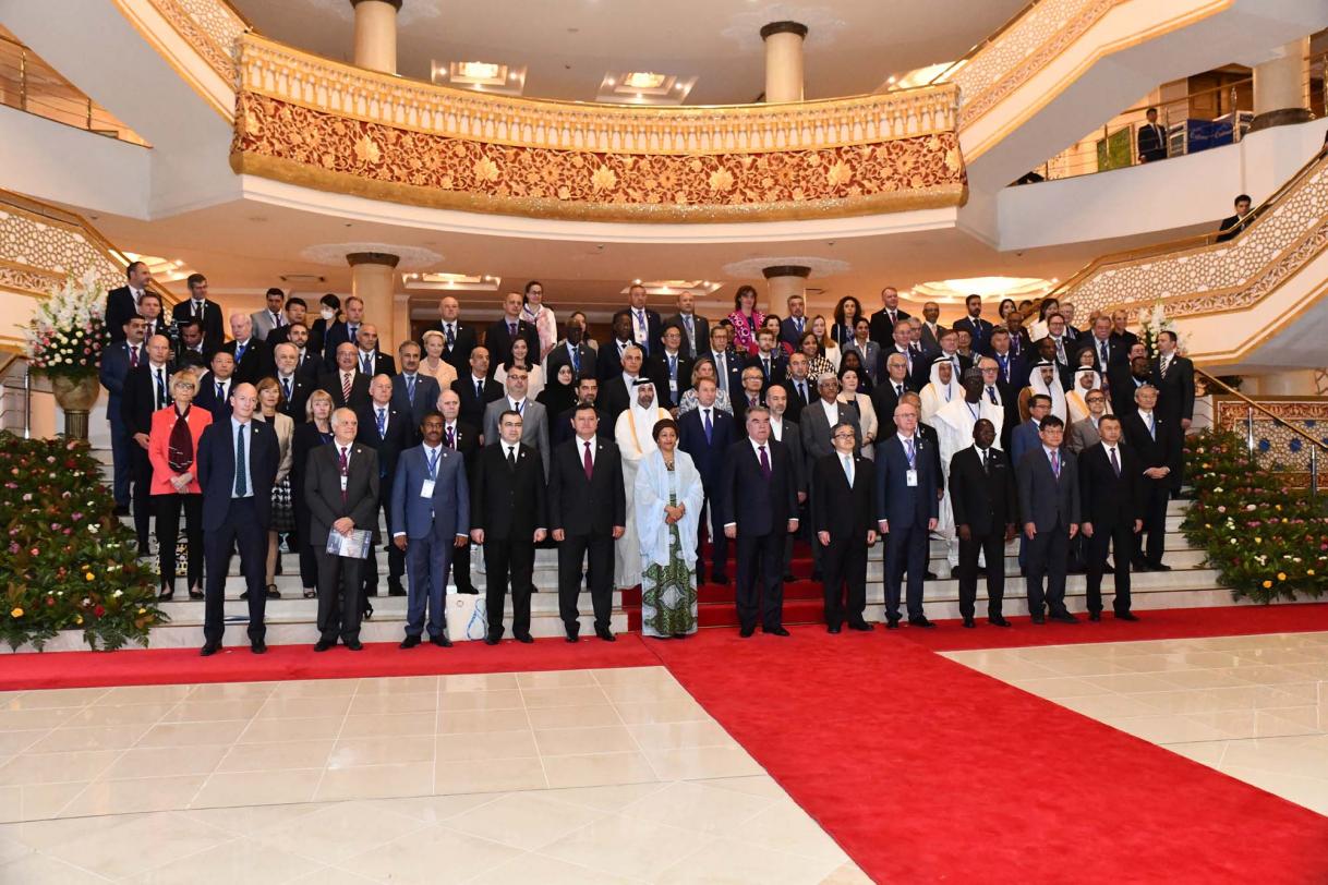 A group of people standing and posing for the camera in a stairway, which is draped by red carpet.