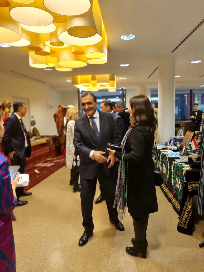 Man in a suit shakes hand with a woman with dark brown hair at shoulder length