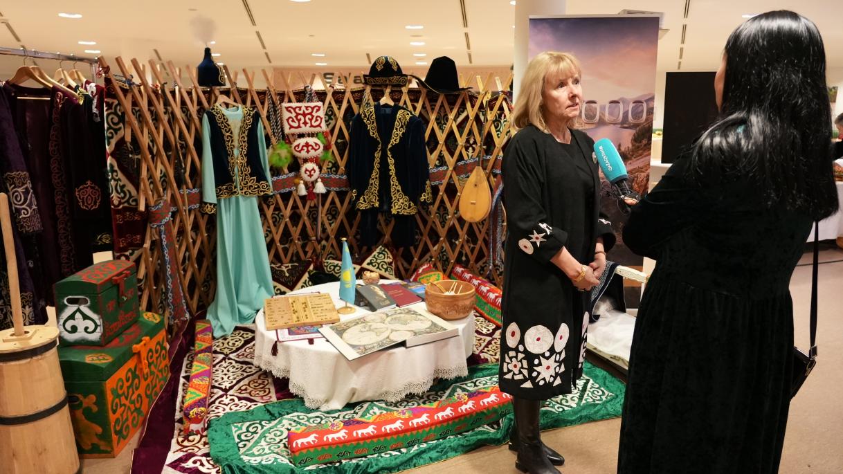 A woman journalist interviews EUSR in front of the Kazakh exhibition stand