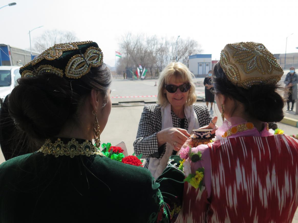 Two people offering beverage to a third person who is smiling. 