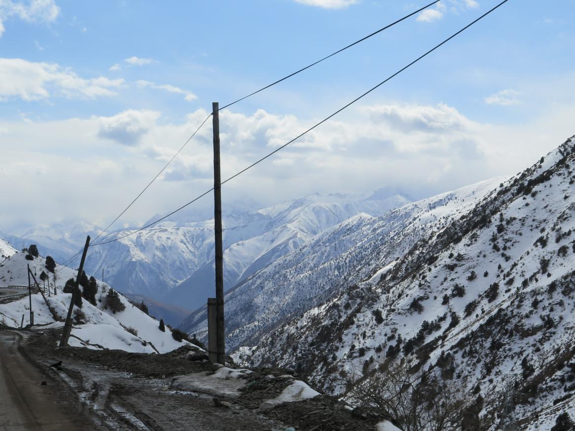 Mountains covered in snow. A road and a powerline along the slope.