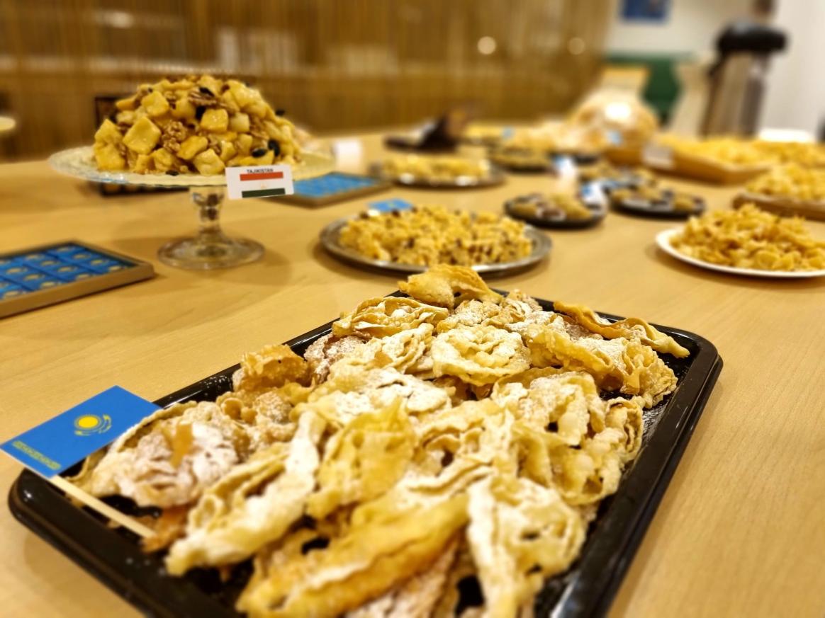 Close up on sweets laid on a black tray with a Kazakh flag on the left side, other sweets in the background are blurry