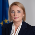 Headshot of Jovita Neliupsiene with EU flag in the background.