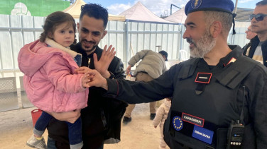 EU officer greeting a man holding a child at a crossing area.
