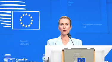 Kaja Kallas stands against a blue EU background. 