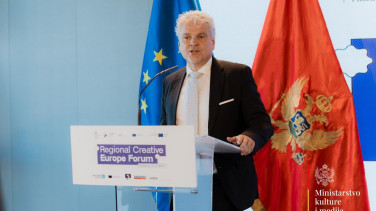 Ambassador Sattler standing behind lectern and speaking