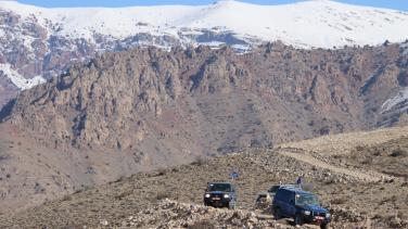 Several road vehicles on mountain terrain.