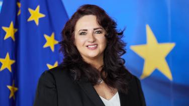head shot of person with EU flag behind
