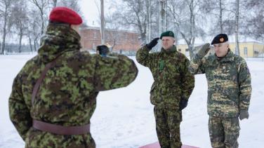 Two senior soldiers salute soldier with back to us, snowy day. 