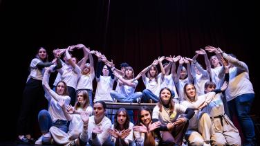 A group of highschool studends from Bar and Tuzla performing in a theatre play and forming with thair hands the sign of a heart.