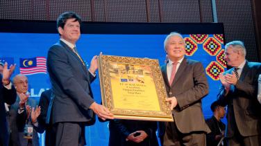 EU Ambassador Rokas and DPM of Sarawak on stage showing a token of appreciation together.
