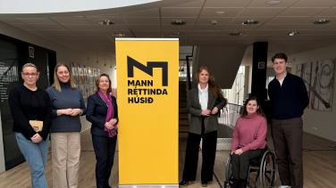 Picture of 6 people standing next to a yellow banner featuring a company logo. 