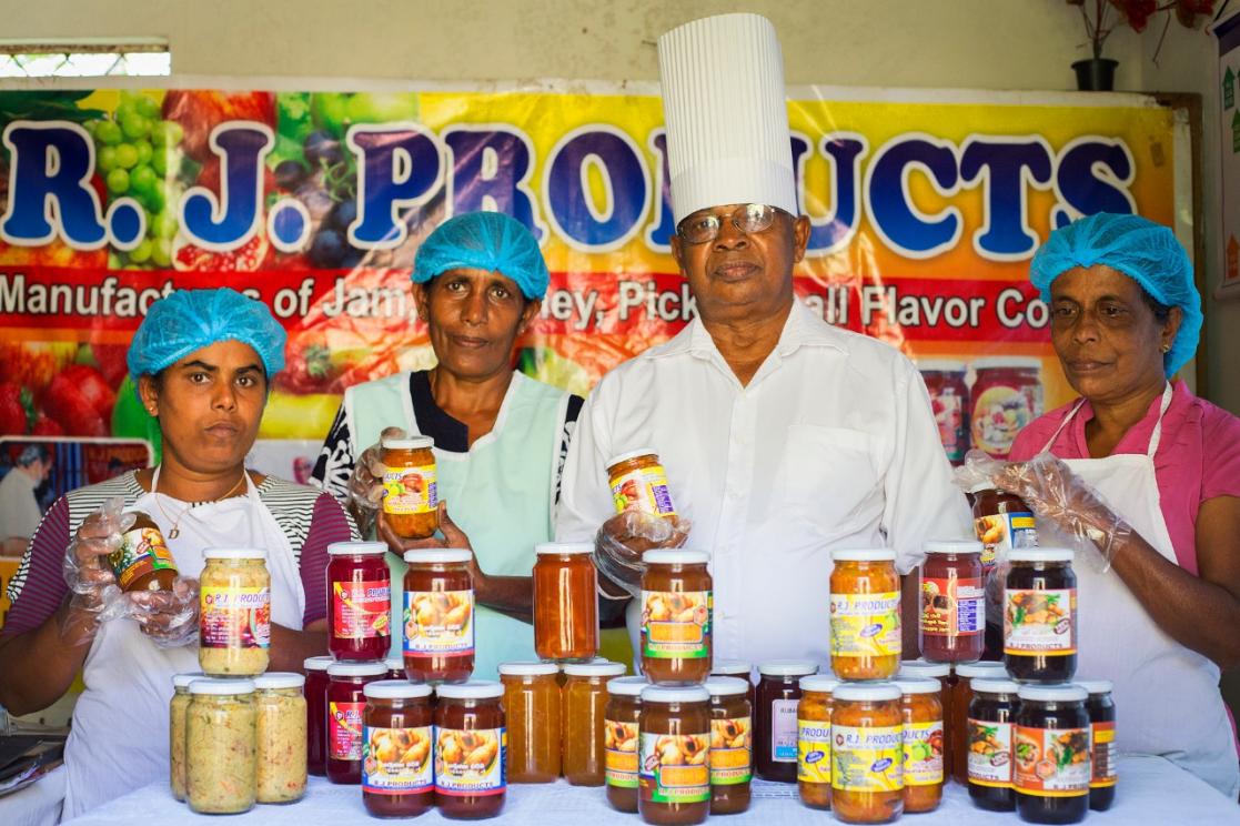 Three women and one man posing with canning jars
