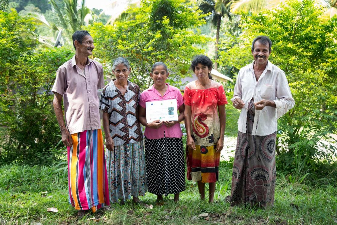 Two men and three women posing, one of them holding a diploma