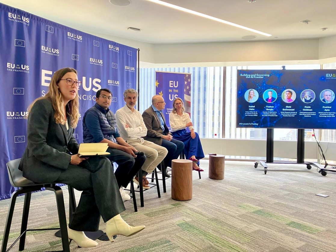 Five people are seated on chairs in a panel format.