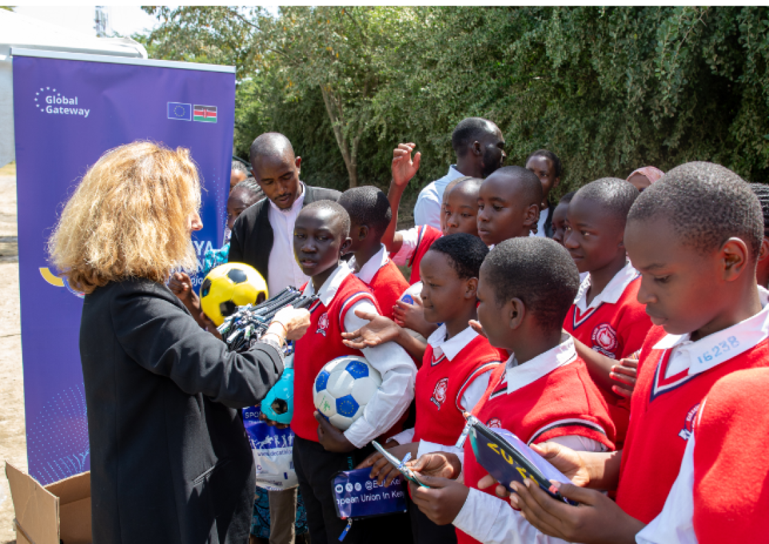 EU team presents footballs and other items to the students