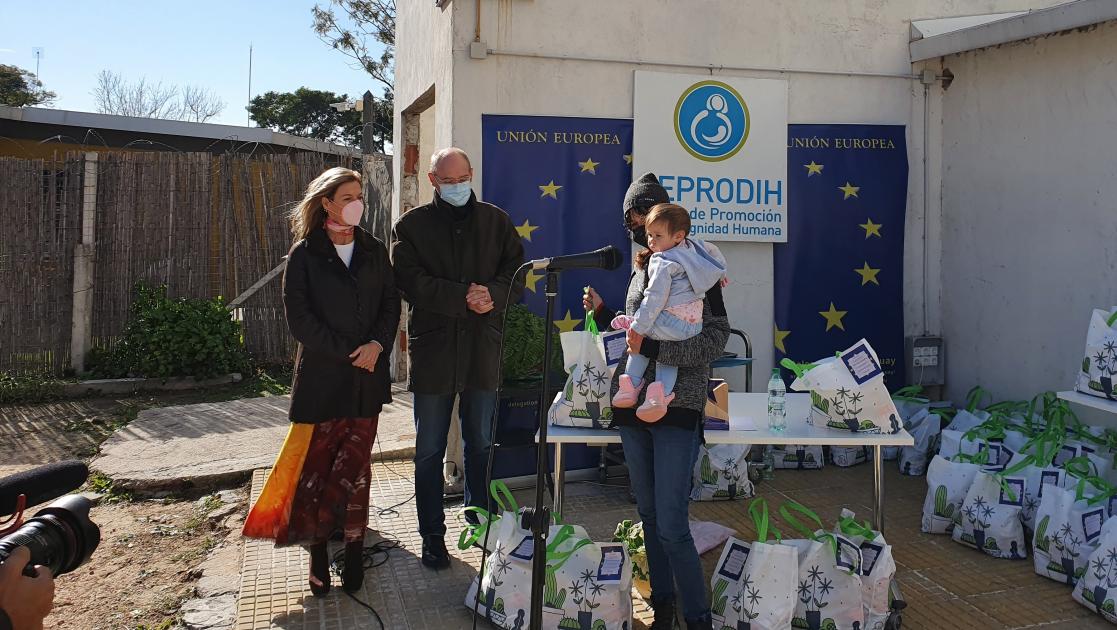People speking to each other next to a table full of bags