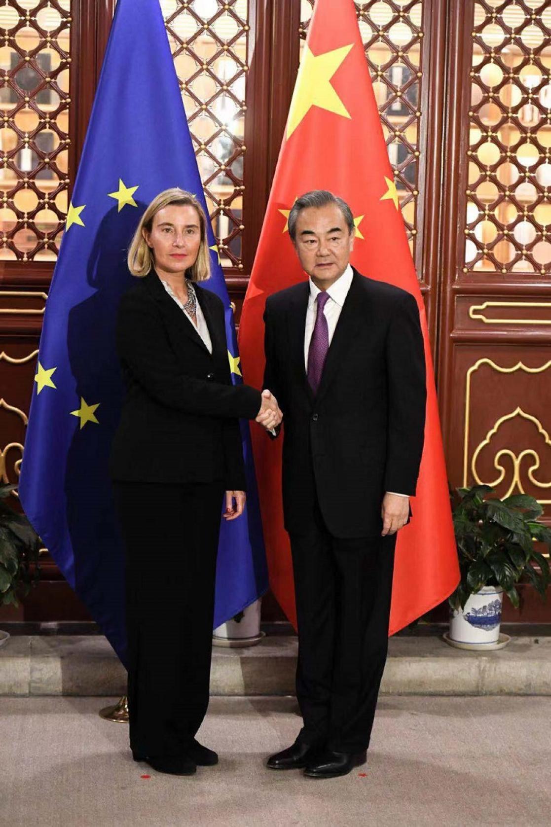 Woman and man posing in front of two flags