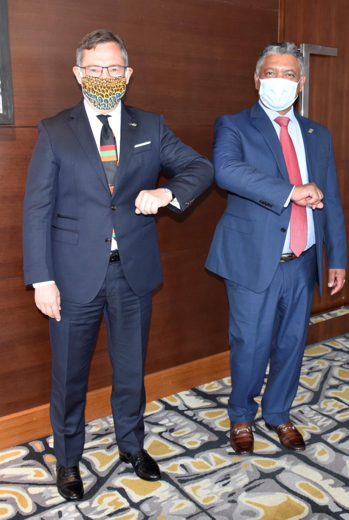 Two men in sanitary masks, bumping elbows in greeting