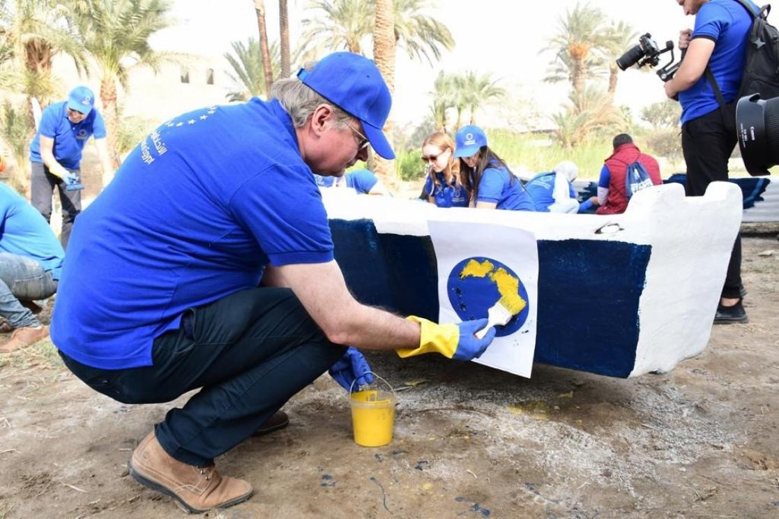 Man wearing blue T-shirt and cap painting the Eu flag