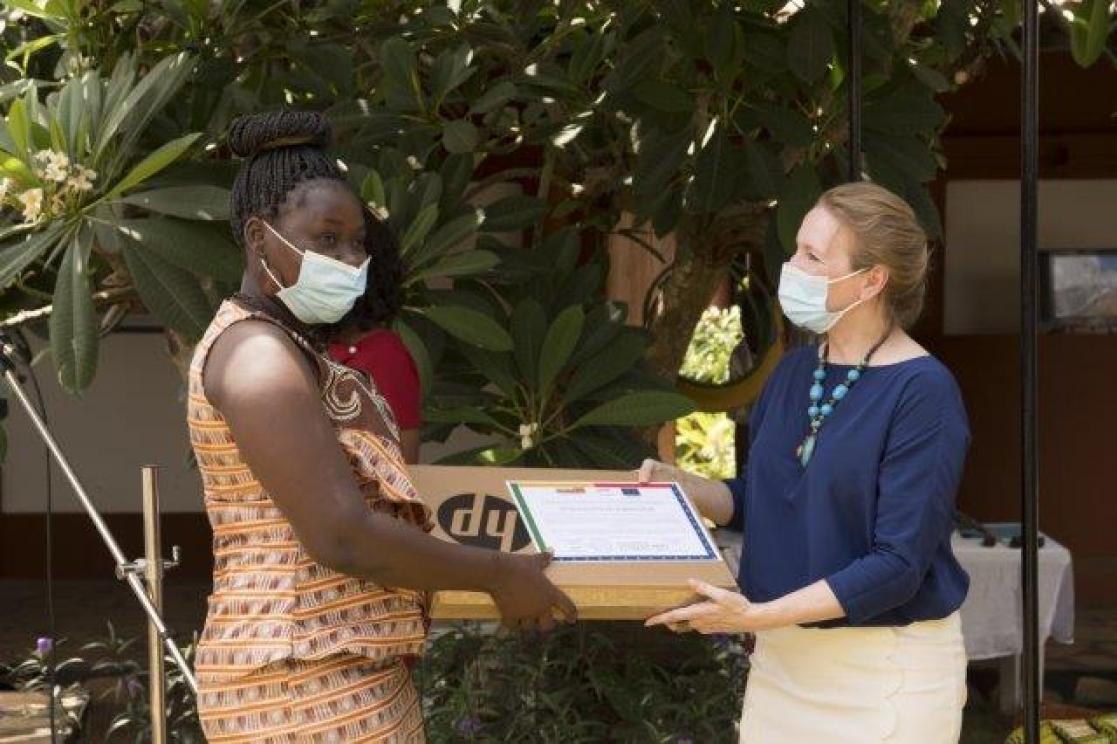 Woman handing another woman a box with a computer in it.