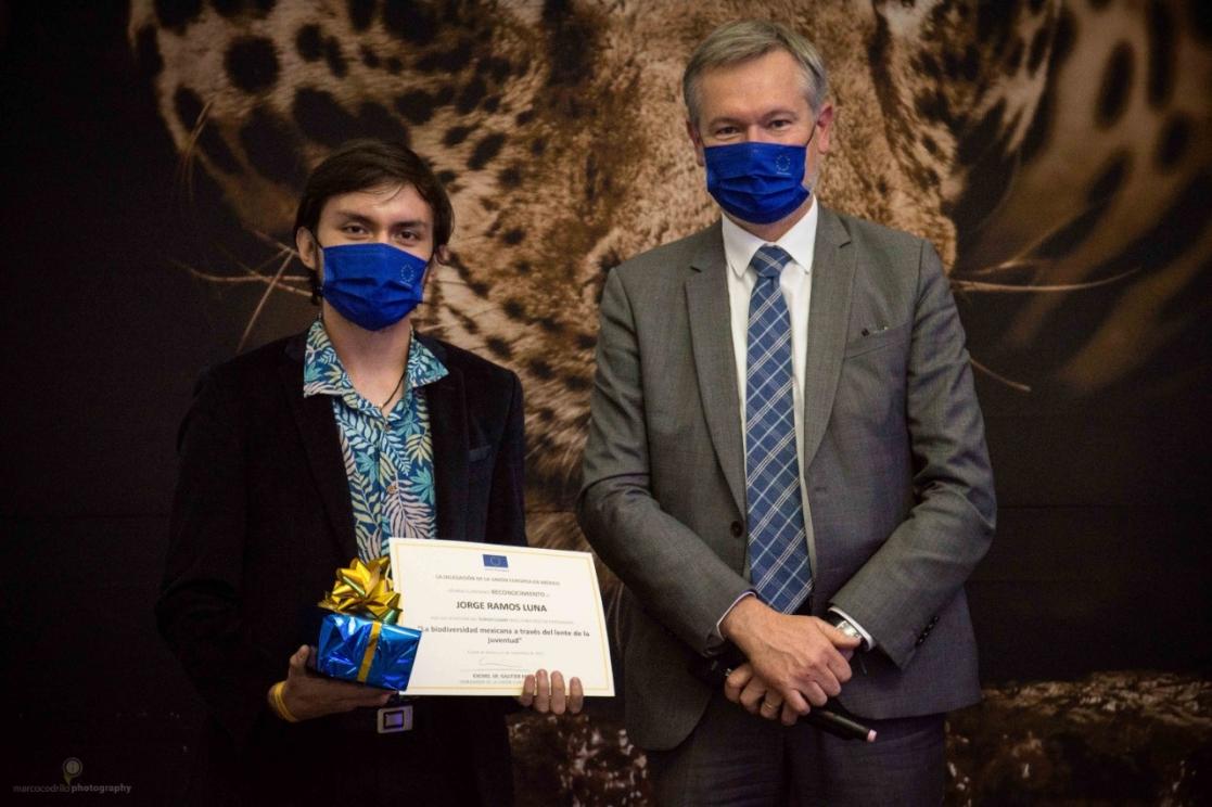 Two men posing, one of them holding an award