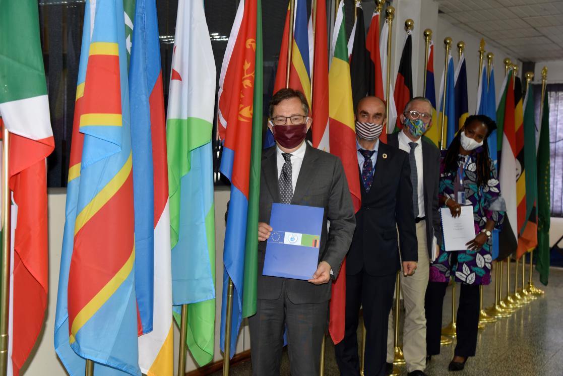 Three men and a woman posing near flags