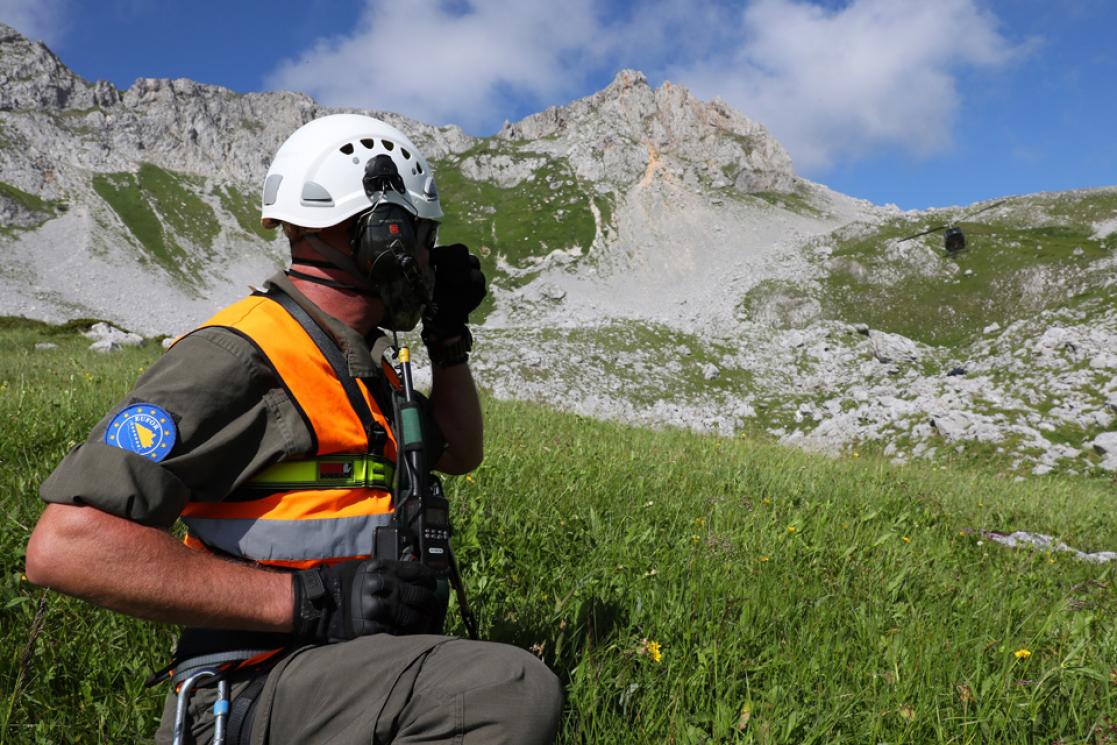 Military on a mountain looking at a helicopter