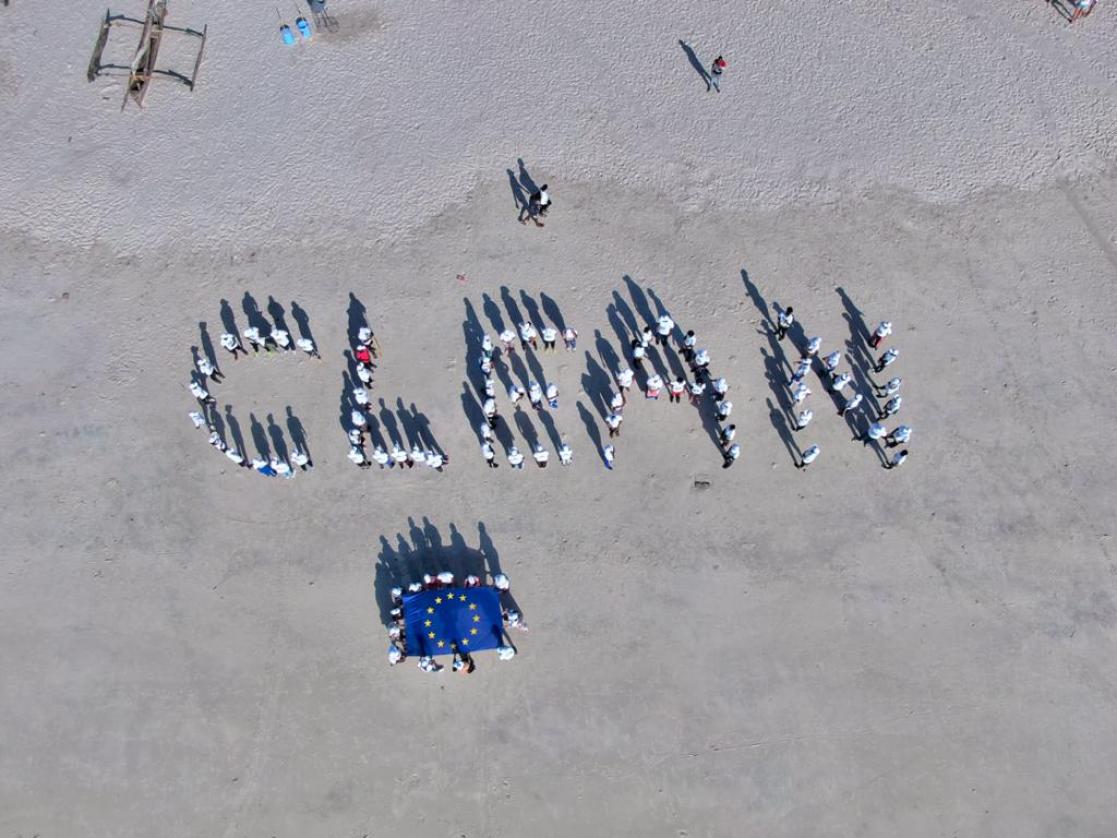 People forming the word "Clean" on the beach