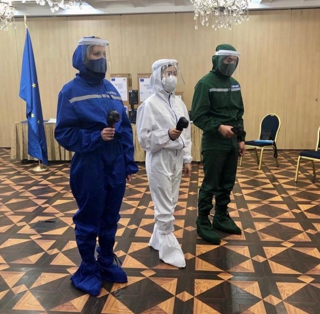 three people wearing control suit of covid
