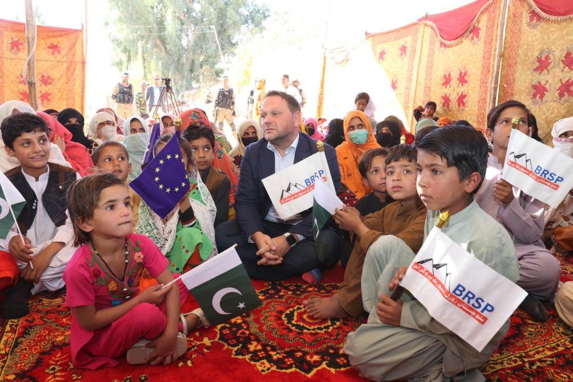 Man sitting on a carpet surrounded by children with banners