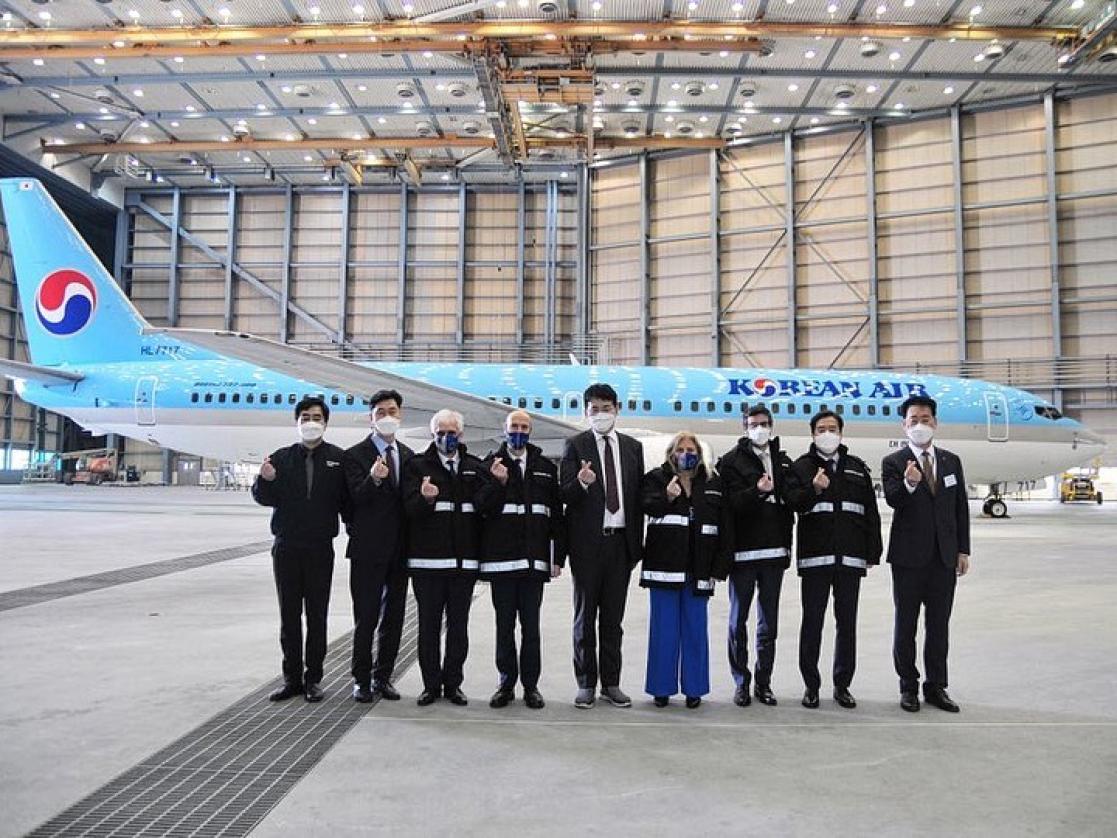Group of people being photographed with an Korean Air aircraft behind them