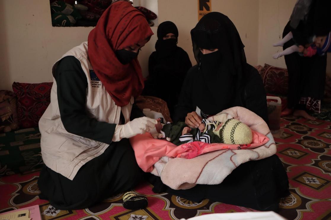 Women sitting on rugs caring for a baby