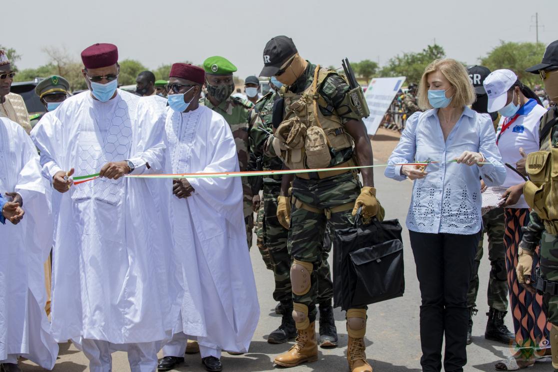 Woman cutting an inauguration ribbon surrounded by people