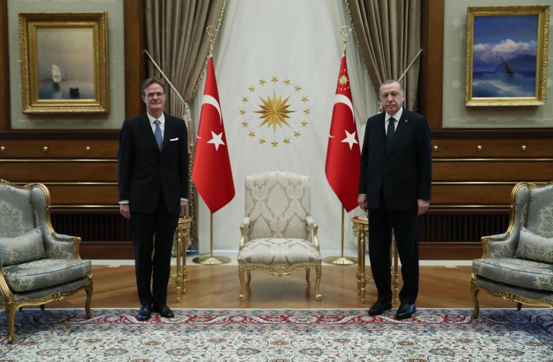 Two people posing for a photo with turkey flag behind