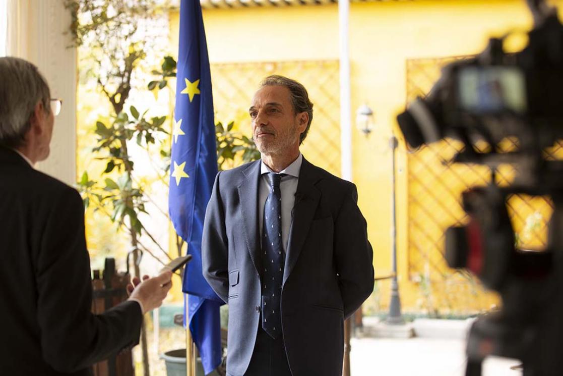 Two men talking being filmed by a video camera