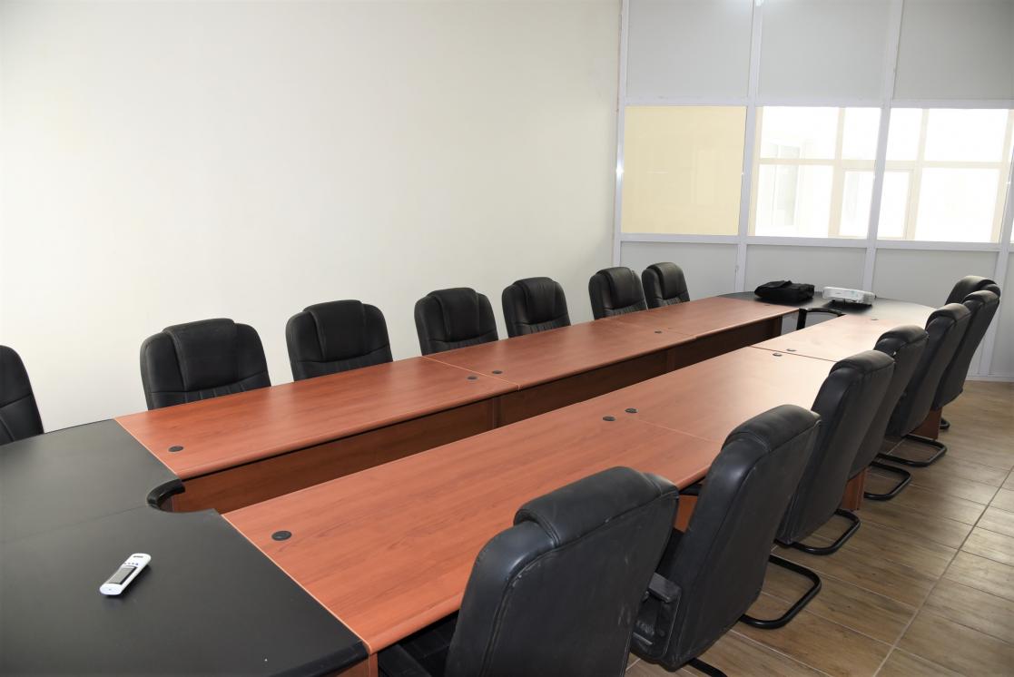 Meeting room consisting of a long wooden table and several black chairs