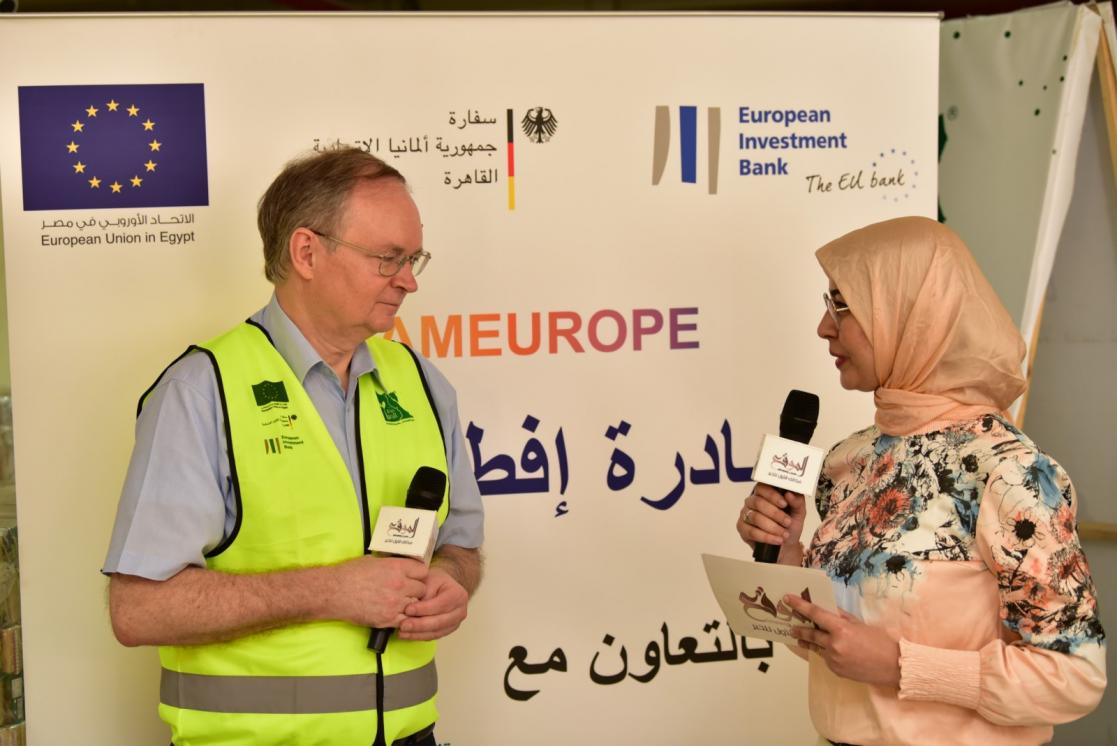 Journalist interviewing a man who wears a safety waistcoat