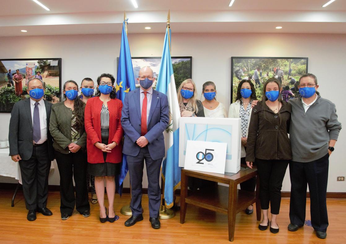 Group of people with sanitary masks posing with the EU flag and a blue and white flag