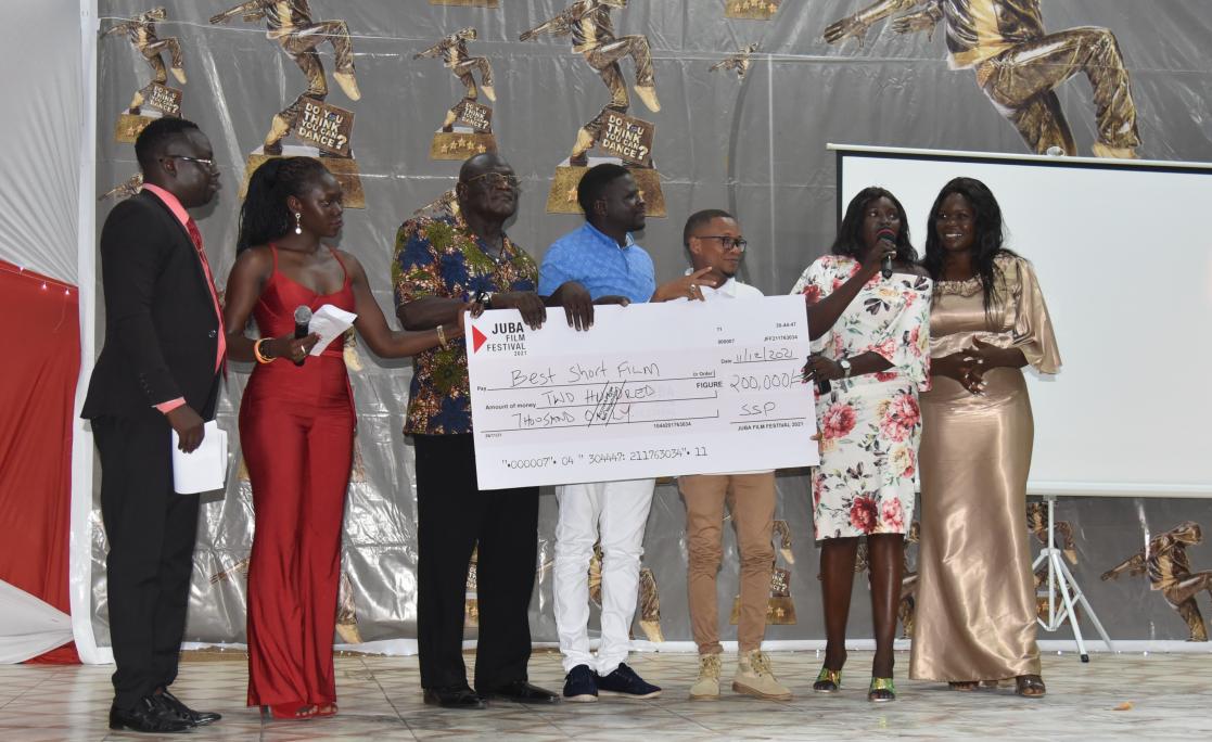 Seven people posing with a cheque in their hands