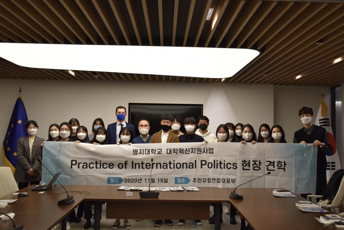 A group of people hold a poster on Practice of International Politics