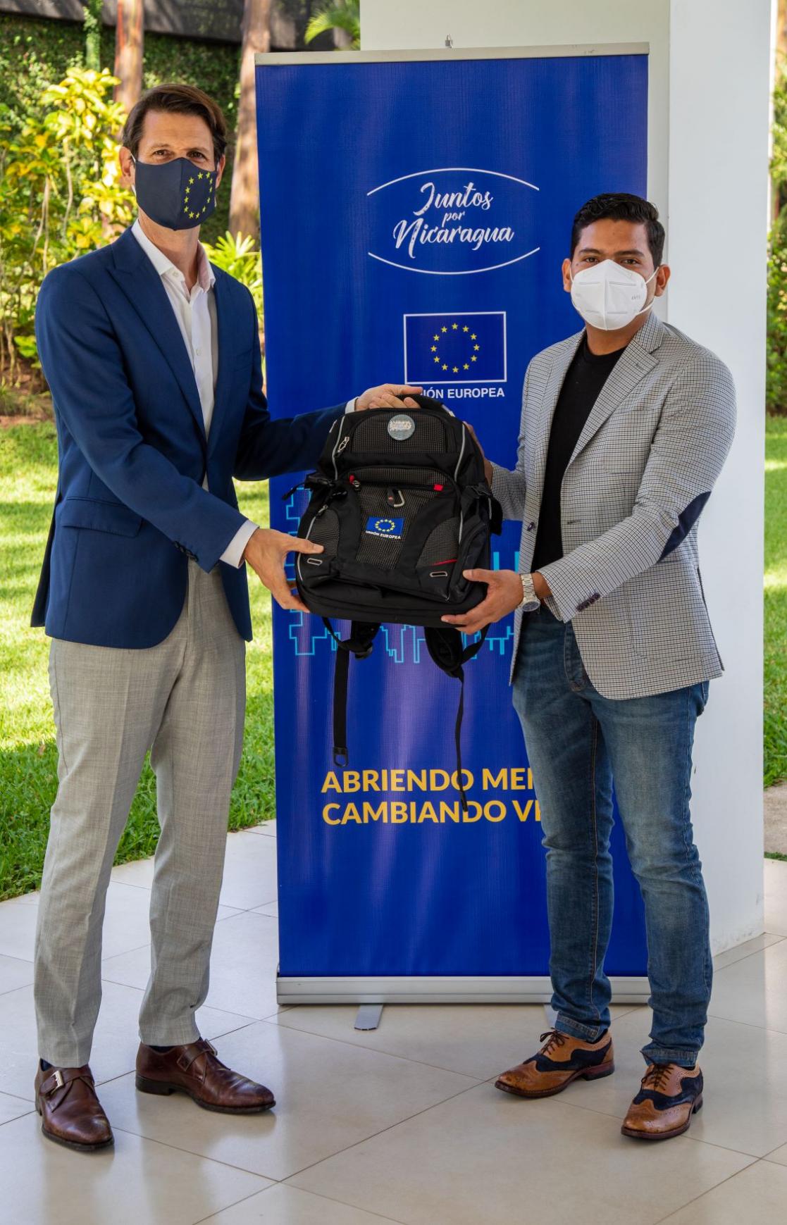 Two men holding a backpack