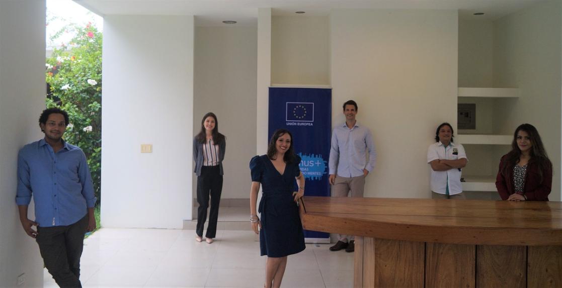 group of people all around a room all standing up looking at the camera